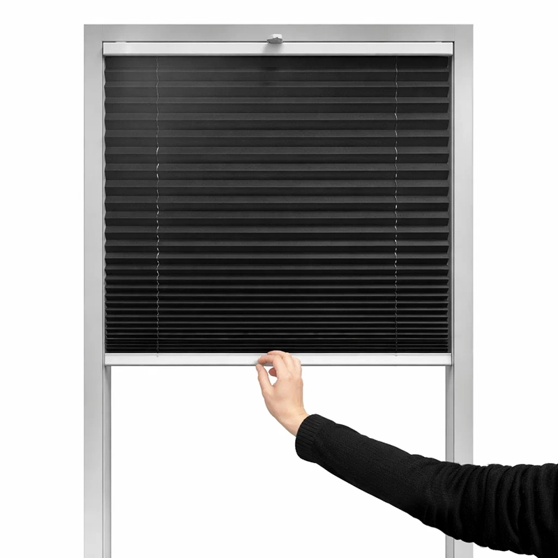 Kéz felülről lefelé húzza a pliszé rolót az ablak árnyékolásának beállításához.