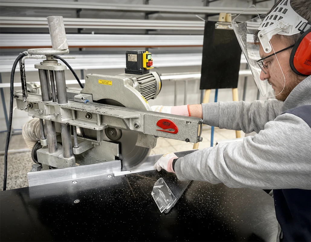 Pliszé szúnyogháló gyártása – méretre vágott alumínium keret egy műhelyben.